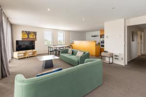 a living room with a green couch and a table at Quest Cathedral Junction Serviced Apartments in Christchurch
