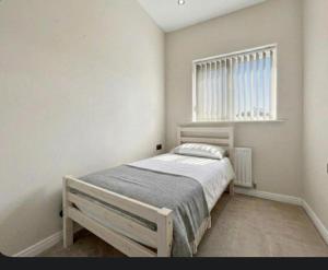 a white bedroom with a bed and a window at Golf Let in Southport