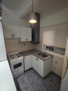 a kitchen with white cabinets and a stove and a sink at Departamento Zarate Centro in Zárate