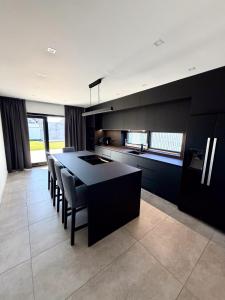 eine Küche mit schwarzen Schränken, einem Tisch und Stühlen in der Unterkunft ASPECT House in Caransebeş
