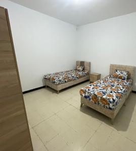 two beds sitting in a room with a wall at Maison Fatima in Mahdia