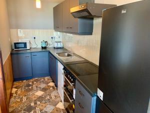a kitchen with blue cabinets and a black refrigerator at Azure Lodge in Bundoran +7 photos