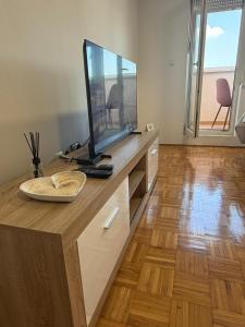 a television sitting on top of a wooden desk at MAAA Apartman in Tuzla +5 photos