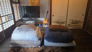 a room with two beds and a guitar in it at ゲストハウス　竹亭 in Marugame