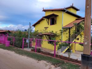 a yellow house with a pink fence in front of it at Casa Encantada in Sêrro