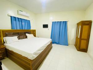 a bedroom with a large bed with blue curtains at Sanga City in Bakel