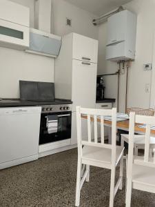 a kitchen with white cabinets and a table and chairs at Wohnung Karl-Marx 1 in Trier