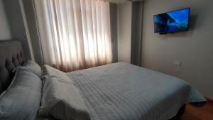 a bedroom with a bed and a flat screen tv at Apartamento Flores in Puno +31 photos