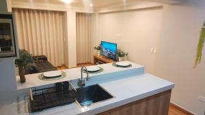 a kitchen with a sink and a living room at Apartamento Flores in Puno
