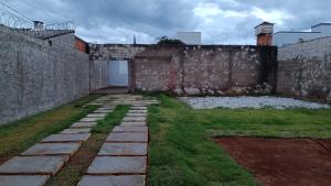 a garden with a stone wall and green grass at Casa inteira, Nações in Patrocínio