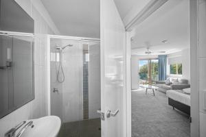 a white bathroom with a shower and a sink at The Dorsal Boutique Hotel in Forster +35 photos