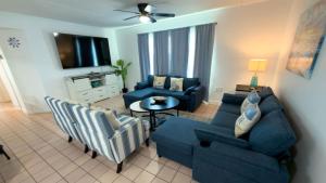 a living room with a blue couch and chairs at Walkable Location - 99 Steps to Beach - Pool apts in South Padre Island