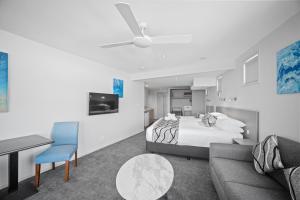 a bedroom with a bed and a couch and a table at The Dorsal Boutique Hotel in Forster