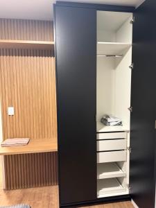 a closet with a black door and white shelves at Meu cantinho in Dourados +10 photos