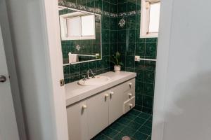 a green tiled bathroom with a sink and a mirror at The Retreat on Piper in Tamworth +9 photos