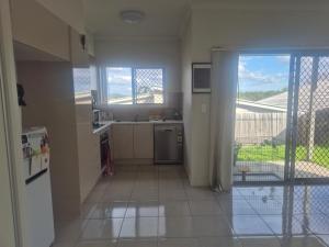 a kitchen with a sink and a refrigerator and a window at One Bedroom One Bathroom Unit With a New TV in Wulkuraka