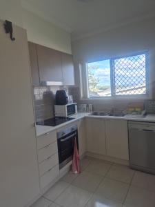 a kitchen with white cabinets and a sink and a microwave at One Bedroom One Bathroom Unit With a New TV in Wulkuraka