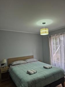 a bedroom with a bed with a green blanket and a window at Cabaña arenal in Pucón