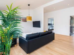 a black couch in a living room with a plant at Saltum Beach Luxury & Wellness in Saltum