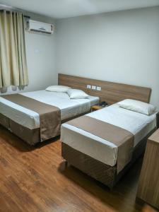 two beds in a room with wood floors at Arca's Hotel Umuarama in Umuarama