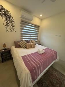 a bedroom with a bed with a striped blanket and a window at SEA Villa With Private Plunge Pool in Todos Santos