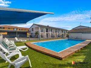 a swimming pool with lounge chairs in a yard at Iluka Villa 2 in Iluka