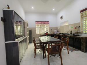 a large kitchen with a table and chairs in it at Redhousehomestay in Kota Bharu
