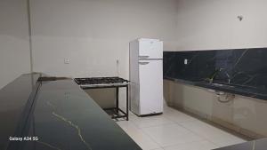 a kitchen with a white refrigerator and a counter at Happy day chácaras in Uberlândia