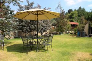 a table and chairs under an umbrella in a yard at ValZur Hospedaje-Habitación Acacias in Villa del Carbón
