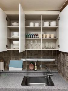 a kitchen with a sink and white cabinets with dishes at 스테이일룸 in Sŭngch'ŏn-ni