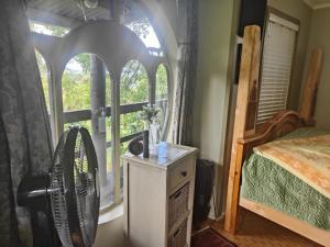 a bedroom with a bed and a window with a fan at garden cabin in Waikino
