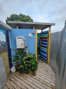 a blue building with a fence and some plants at garden cabin in Waikino