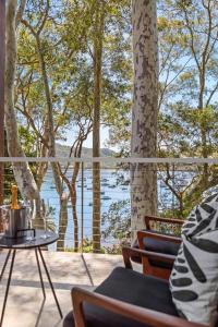 a porch with a view of a lake and trees at The Treehouse Avalon in Whale Beach