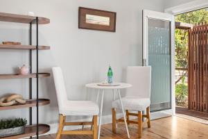 a table and chairs in a room with a window at The Treehouse Avalon in Whale Beach +4 photos