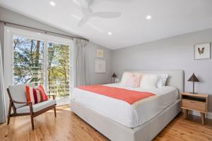 a white bedroom with a large bed and a window at The Treehouse Avalon in Whale Beach