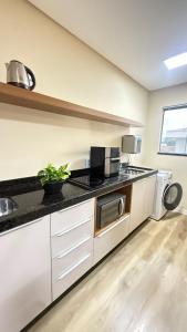 a kitchen with white cabinets and a black counter top at Studio no centro de Pomerode! in Pomerode