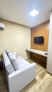 a living room with a white couch and a tv at Studio no centro de Pomerode! in Pomerode