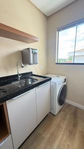 a kitchen with a sink and a washing machine at Studio no centro de Pomerode! in Pomerode +9 photos