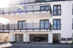 a white building with a balcony and a car parked at Penthouse & Forest Retreat - near city in Bornheim