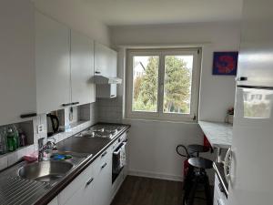 a kitchen with white cabinets and a sink and a window at TheCrown in Kilchberg
