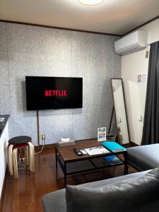 a living room with a tv on a wall at Stay Plus Azunoa in Oyama