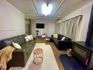 a living room with a green couch and a television at Lahool Cottage in Stanthorpe