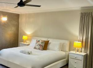 a bedroom with a white bed with two lamps at Lahool Cottage in Stanthorpe