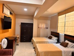 a hotel room with two beds and a flat screen tv at Gran Hotel Ica in Ica