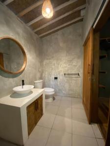 a bathroom with a sink and a toilet and a mirror at Seenau House Bali in Selemadeg