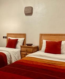 a hotel room with two beds with red pillows at Tayafut ApartmentTerrace in Mirleft
