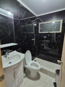 a black bathroom with a toilet and a sink at Cabañas del cerro sombrero in Arica +9 photos