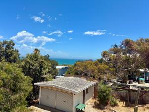 a small white house with the ocean in the background at Kite House in Guilderton
