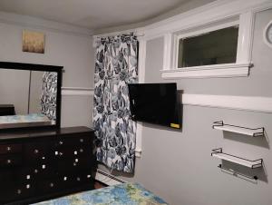 a bedroom with a tv on the wall and a dresser at Grove#9 in Irvington