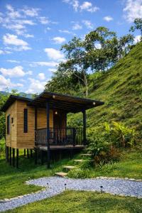a cabin on a hill with a deck and a path at Refugio La Tángara del Río in Cocorná